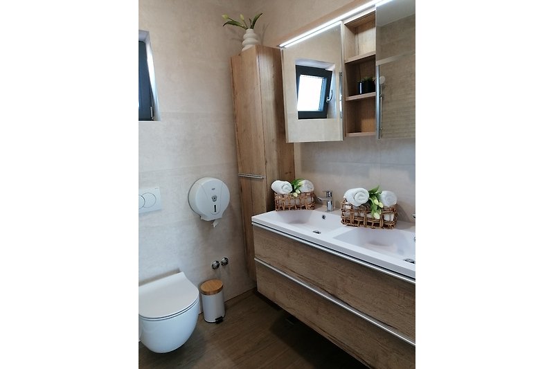 Modernes Badezimmer mit Spiegel, Waschbecken und Pflanze.