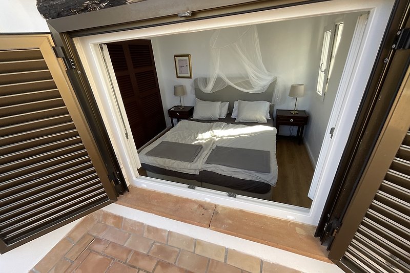 Schlafzimmer mit Doppelbett und Zugang zur Terrasse .