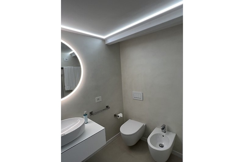 Modernes Badezimmer mit ovaler Badewanne und Glasdusche.