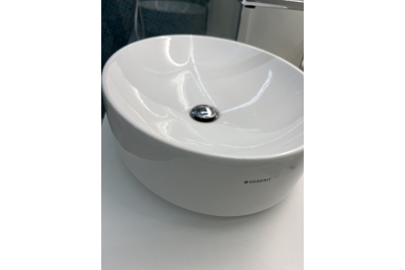Kreisförmiges Waschbecken, ovale Badewanne, moderne Audioausstattung.