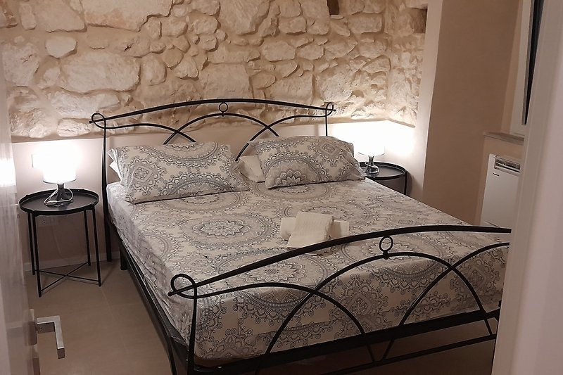 Modernes Schlafzimmer mit Holzbett und Lampen. Gemütliche Bettwäsche.