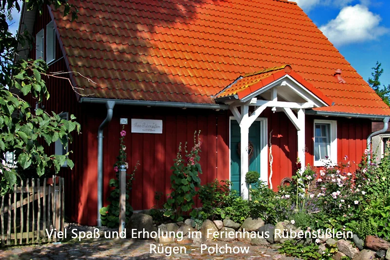 Traditionelles Haus mit Garten, Bäumen und Zaun. Ruhige Dorfatmosphäre.