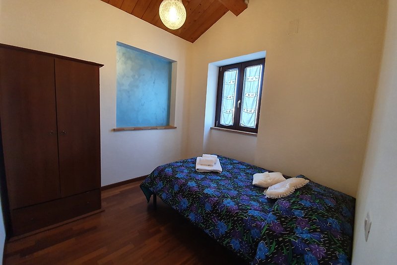 Schlafzimmer mit Holzbett, Fenster und Bettwäsche - stilvoll eingerichtet!