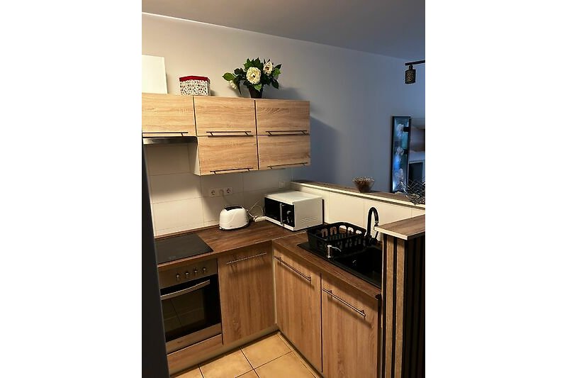 Moderne Küche mit Holzschränken, Arbeitsplatte und Küchengeräten.