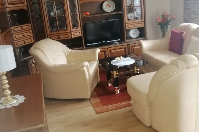 Wohnzimmer mit bequemer Couch, Tisch, Lampe und Fernseher.
