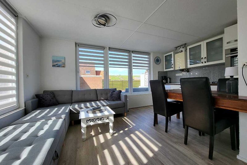 Heller Wohnbereich mit gemütlicher Couch und 2 großen Fensterfronten (mit Deichblick).
