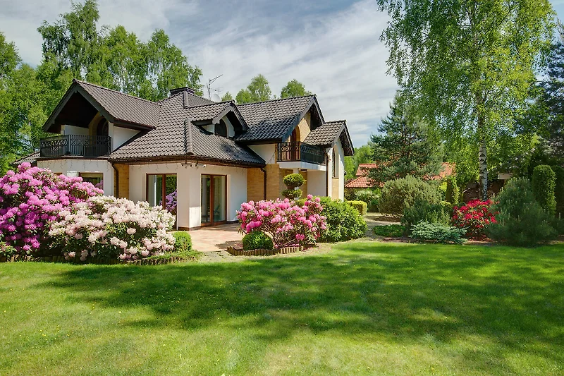 Charmantes Haus mit Garten, Rosen und blühenden Pflanzen.