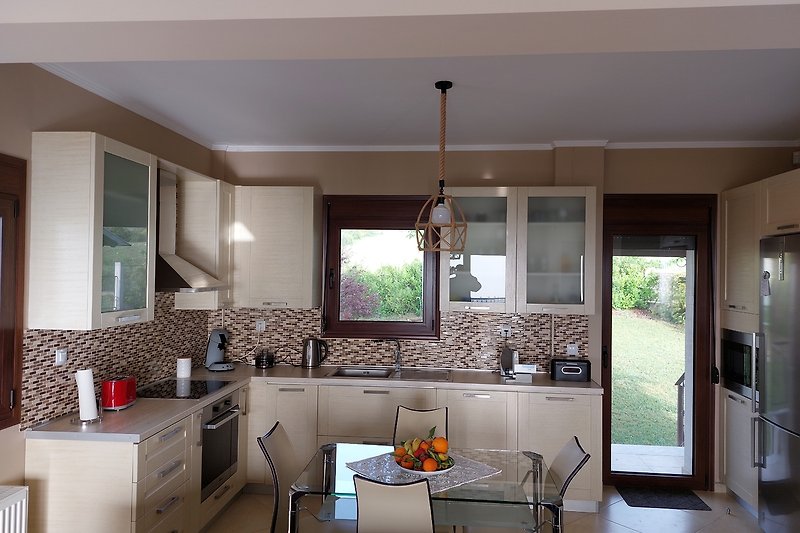 Voll ausgestattete moderne Küche mit Zugang auf eine kleine Terrasse mit Blick auf den Olymp.