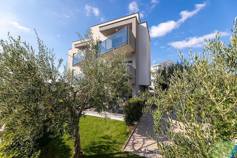 Suburbanes Gebäude mit Garten, Bäumen und Wolken.