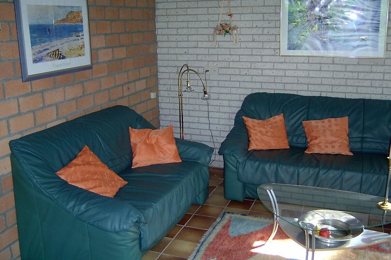Wohnzimmer mit bequemer Couch, Holztisch und Fenster.