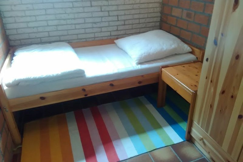 Holzgestaltetes Schlafzimmer mit Etagenbett und Bettwäsche.