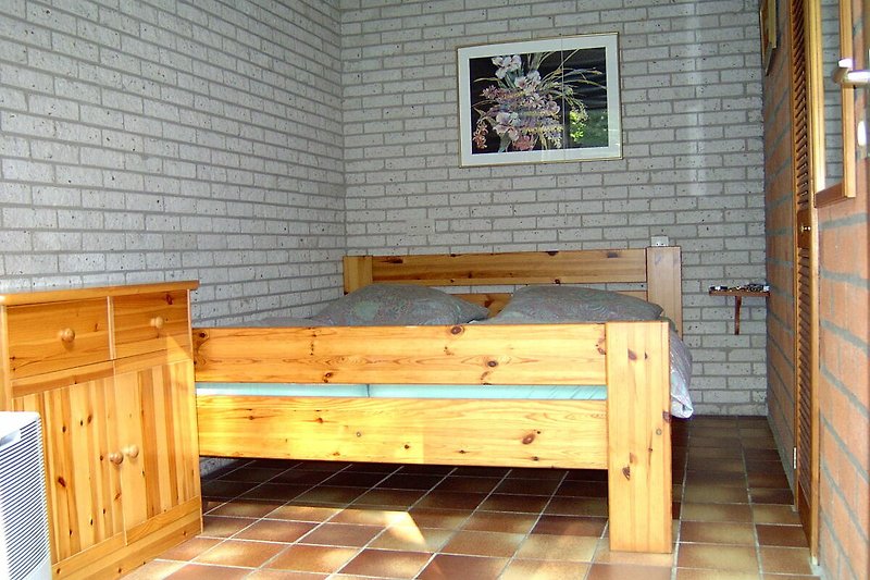Schlafzimmer mit Holzmöbeln, Bett und Schrank, gemütliche Einrichtung.