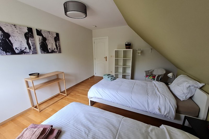Schlafzimmer mit gemütlichem Bett, Holzmöbeln und Lampen.