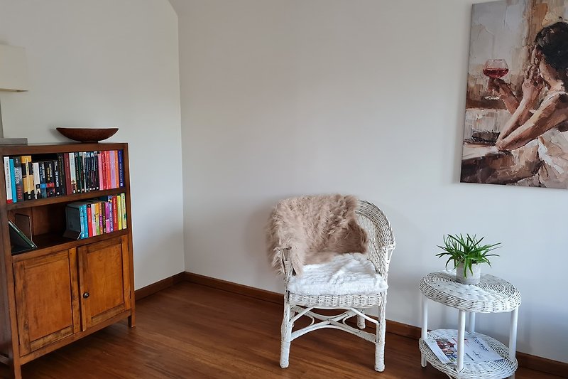 Wohnzimmer mit Holzmöbeln, Bücherregal und Kunst.