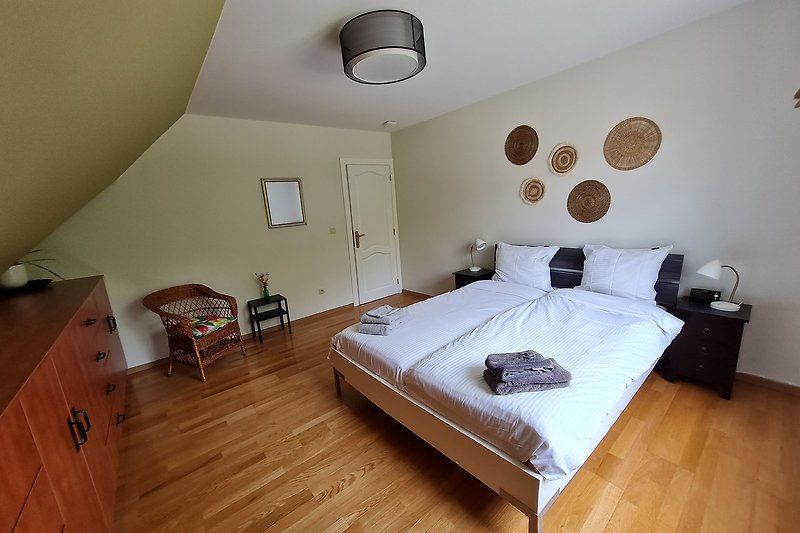 Gemütliches Schlafzimmer mit Holzmöbeln, Bett und Lampen.