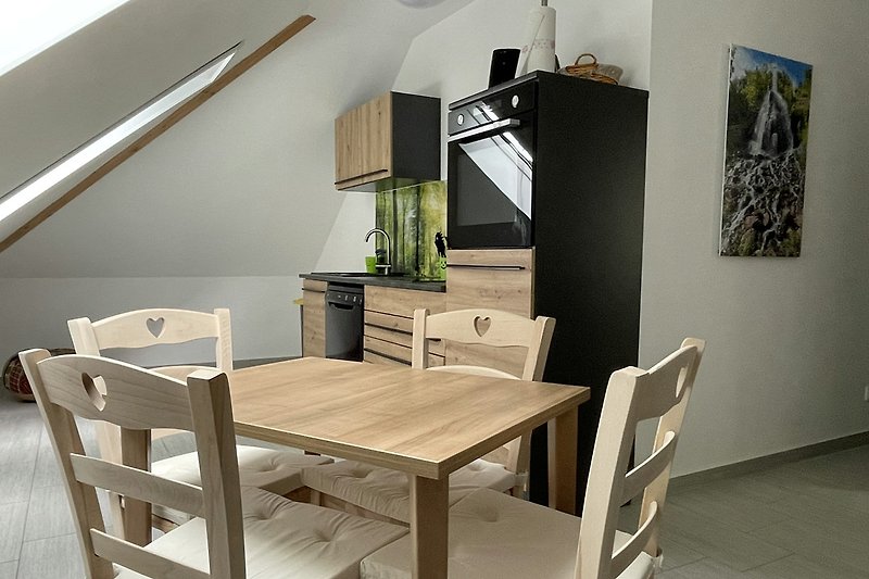 Küche mit Esstisch, Stühlen und Regalen.