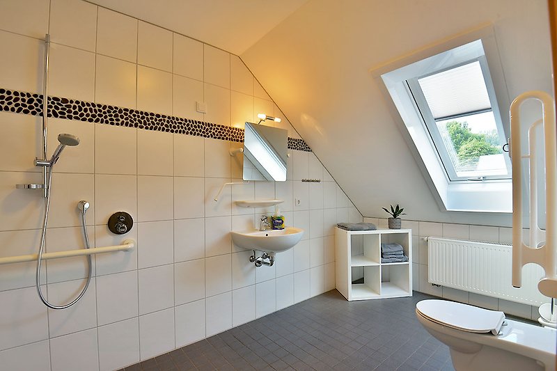 Modernes Badezimmer mit Dusche, Fenster, Pflanze und Armaturen.
