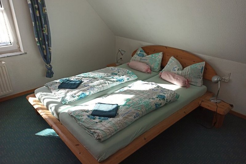 Fenster mit Vorhang und gemütlichem Bett in Schlafzimmer.