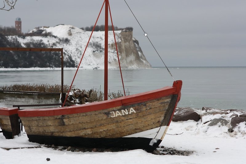 Winterlandschaft mit Boot, Mast und Schnee.
