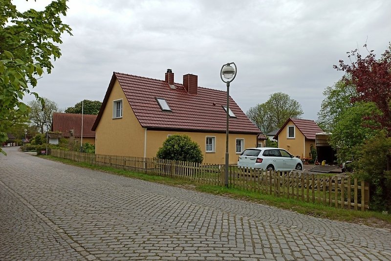 Haus mit grüner Landschaft, Auto und Straße.