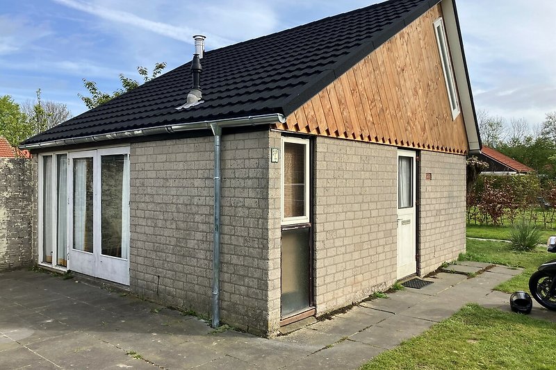 Ländliches Haus mit Garten, Holzhaus und grüner Landschaft.