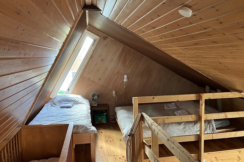 Dachboden mit Holzbalken, Fenster und Leiter.