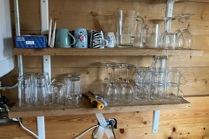 Moderne Bar mit Holzregalen, Glaswaren und Metallwerkzeugen.