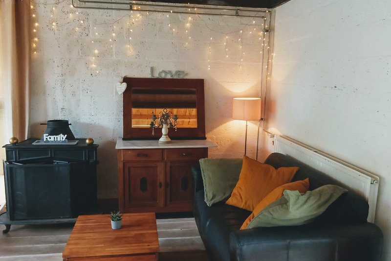 Wohnzimmer mit brauner Couch, Holzmöbeln und Lampen.