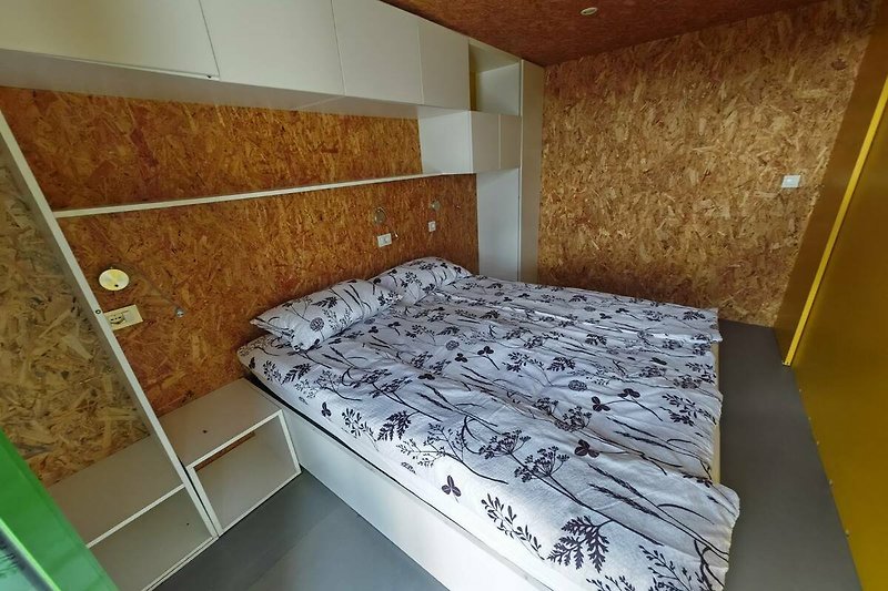 Schlafzimmer mit Holzbett und Metalldecke.