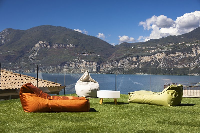 Vista mozzafiato: lago, montagne, cielo e mobili da esterno.