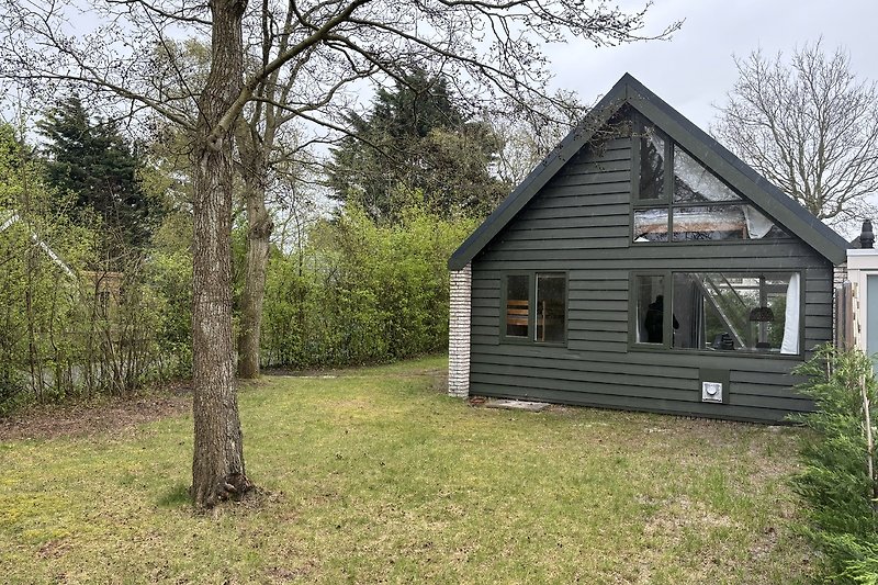 Gemütliches Holzhaus mit Garten, umgeben von Wald und Wiesen.