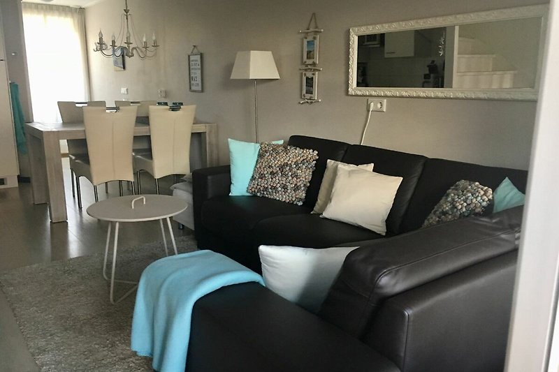 Elegantes Wohnzimmer mit grauem Sofa, Holztisch und stilvoller Beleuchtung.