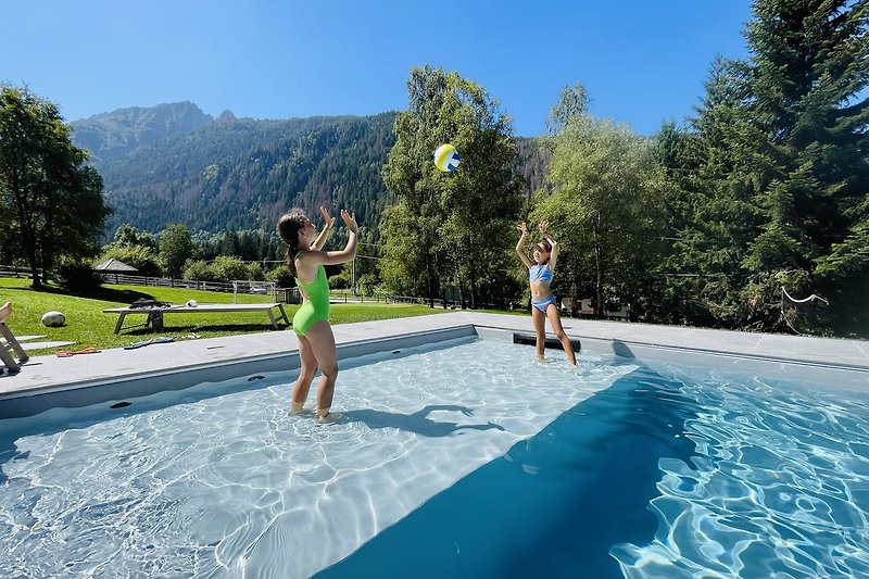 Privater Pool mit Bergblick, umgeben von Palmen und blühenden Pflanzen.