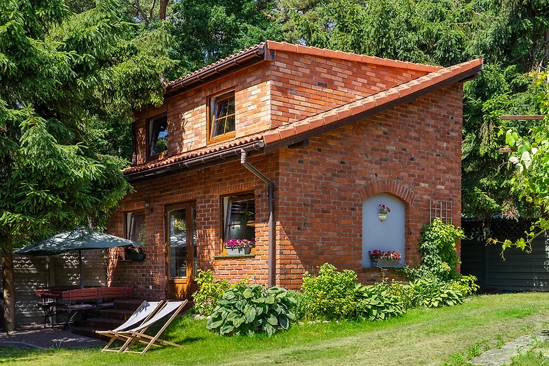 Ländliches Ferienhaus mit Backsteinfassade und Begrünung.