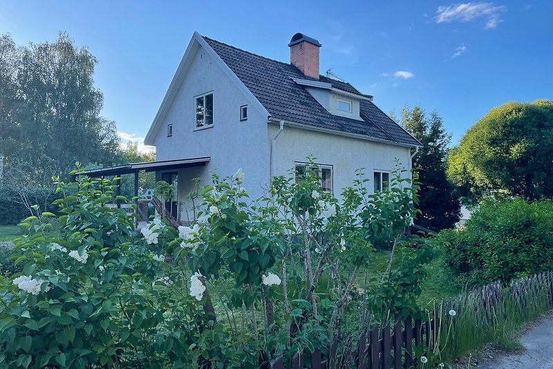 Charmantes Landhaus mit Garten, Blumen und grüner Wiese.