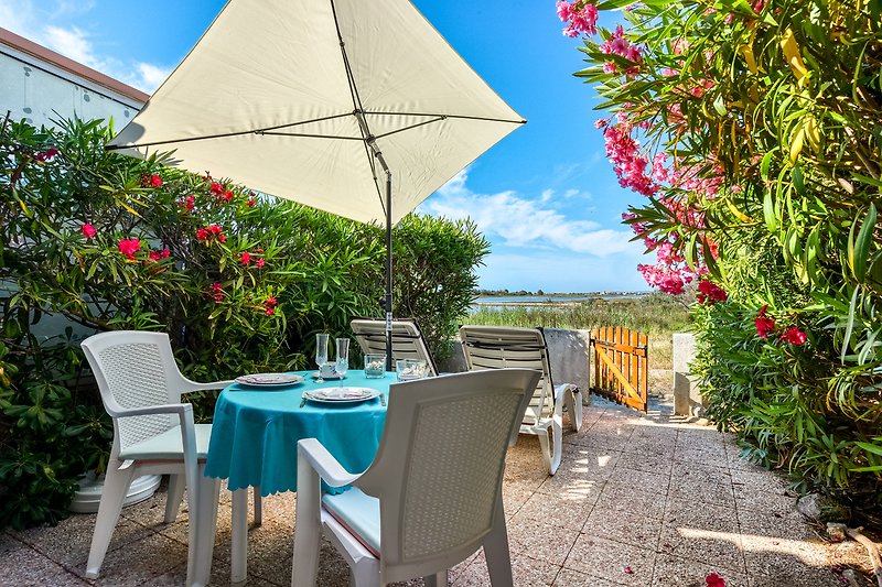 Entspannte Terrasse mit Gartenmöbeln und schattenspendendem Sonnenschirm.