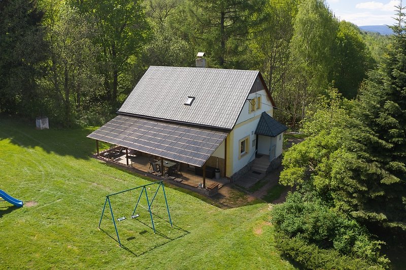 Gemütliche Hütte mit Holzverkleidung, umgeben von Wald und Bergen.