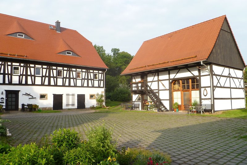 Dreiseitenhof, Ferienhaus mit Garten, Bäumen und blühenden Pflanzen.