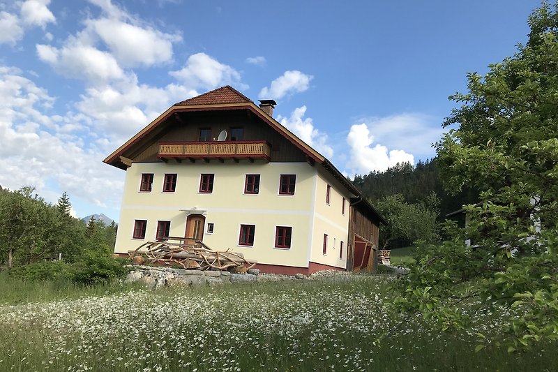 Charmantes Landhaus mit Bergblick, grünem Garten und blühenden Sträuchern.