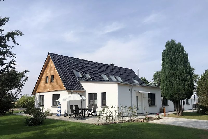 Blick auf das Haus mit der Fewo Terrasse, Parkplatz und Eingang.