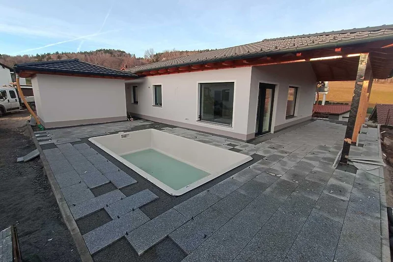 Großer Pool im sonnigen Innenhof mit Einfahrt und markantem Dach.