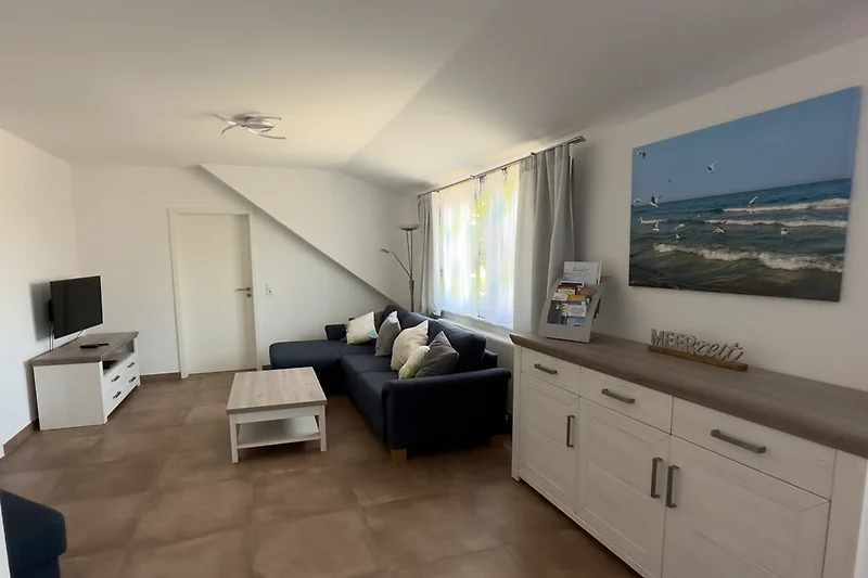 Wohnzimmer mit Holzfußboden, Tagesbett und Flachbildschirm.