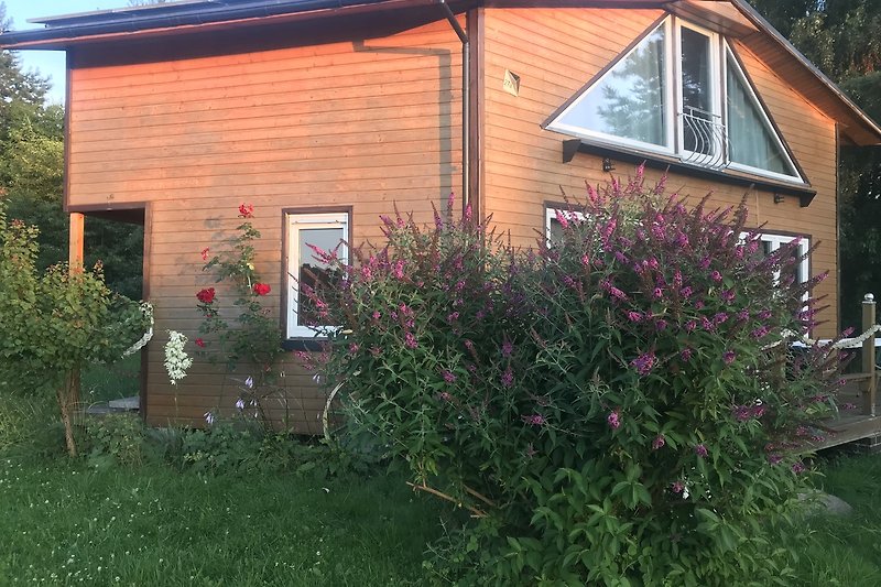 Charmantes Sommerhaus mit blühendem Garten und grüner Umgebung.