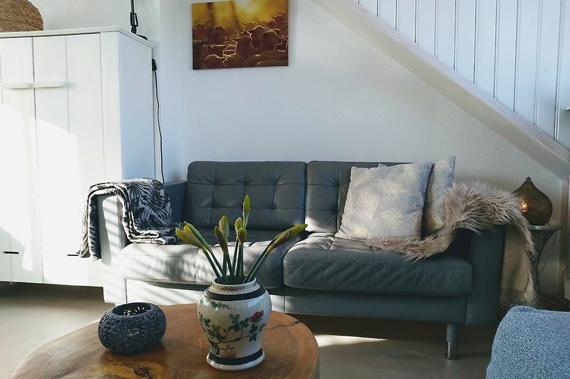 Elegantes Wohnzimmer mit grauem Sofa, Pflanzen und stilvoller Deko.