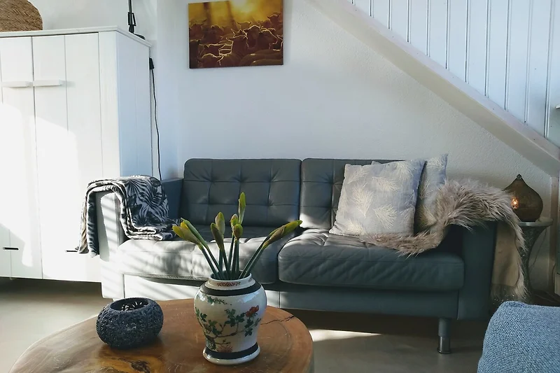 Elegantes Wohnzimmer mit grauem Sofa, Pflanzen und stilvoller Deko.