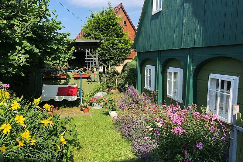 Charmanter Garten mit Blumen, Bäumen und gepflegtem Rasen.