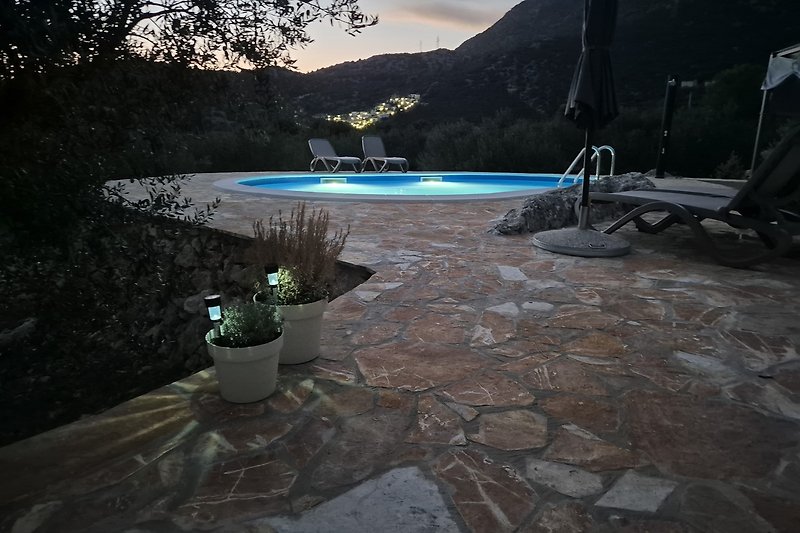 Privater Pool mit tropischen Pflanzen und Bergblick bei Nacht.