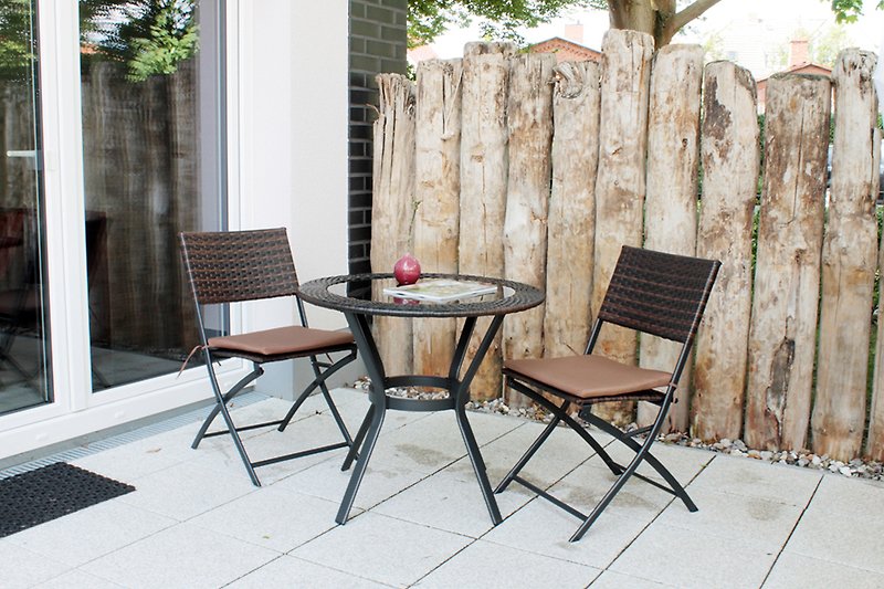 Gemütlicher Garten mit Holzmöbeln, Pflanzen und schattiger Terrasse.