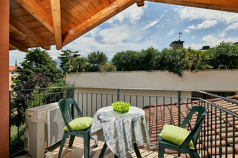 Charmante Terrasse mit Möbeln, grünem Garten und herrlichem Himmel.