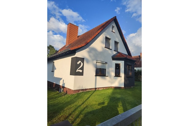 Charmantes Bauernhaus mit Holzfassade, grünem Garten und Hügelblick.